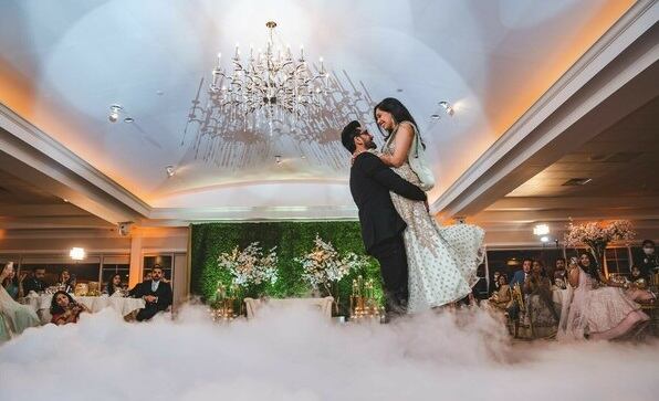 Novios bailando sobre niebla baja, el novio levanta a la novia en el aire